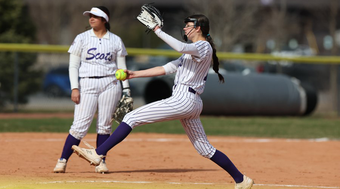 Scots softball pitcher is in mid-throw with a yellow ball in hand, wearing a white pinstriped uniform.