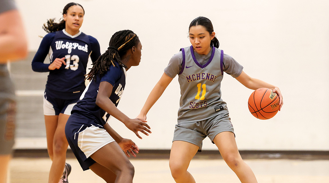 Morgan (#11) dribbles past a defender in a navy Wolfpack jersey during a game. 